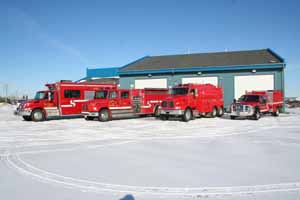 Four fire rescue vehicles parked outside of a fire station